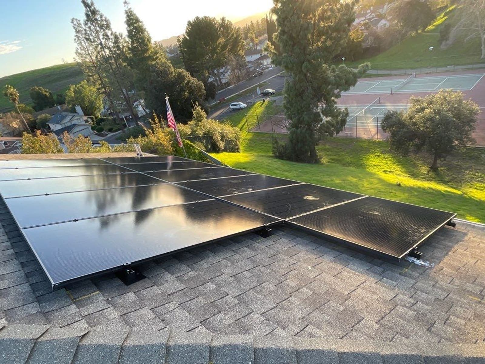 Solar array on a roof above a green hillside and neighbourhood park